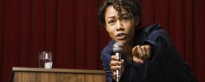 Mixed race businesswoman speaking on stage and pointing